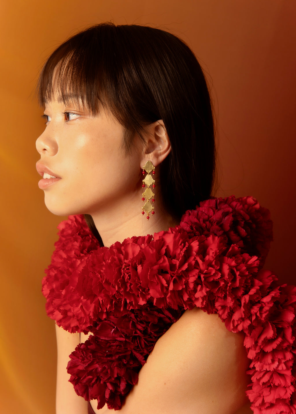 Pendientes largo hechos a mano con piedras rojas, bañados en oro. Foto modelo.