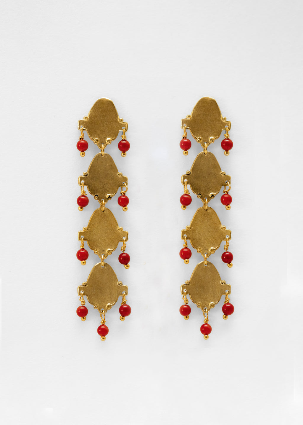 Pendientes largo hechos a mano con piedras rojas, bañados en oro. Foto detalle de producto. 