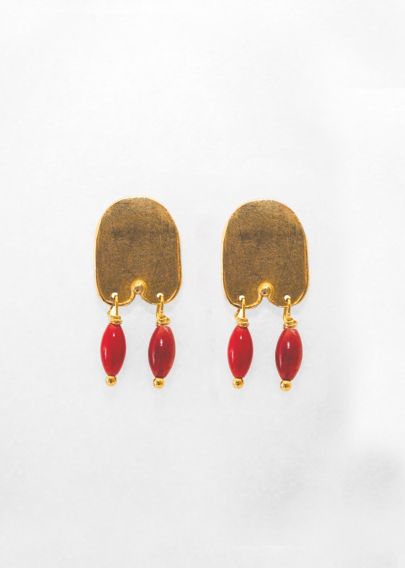 Pendientes hechos a mano con piedras rojas bañado en oro. Foto detalle de producto. 