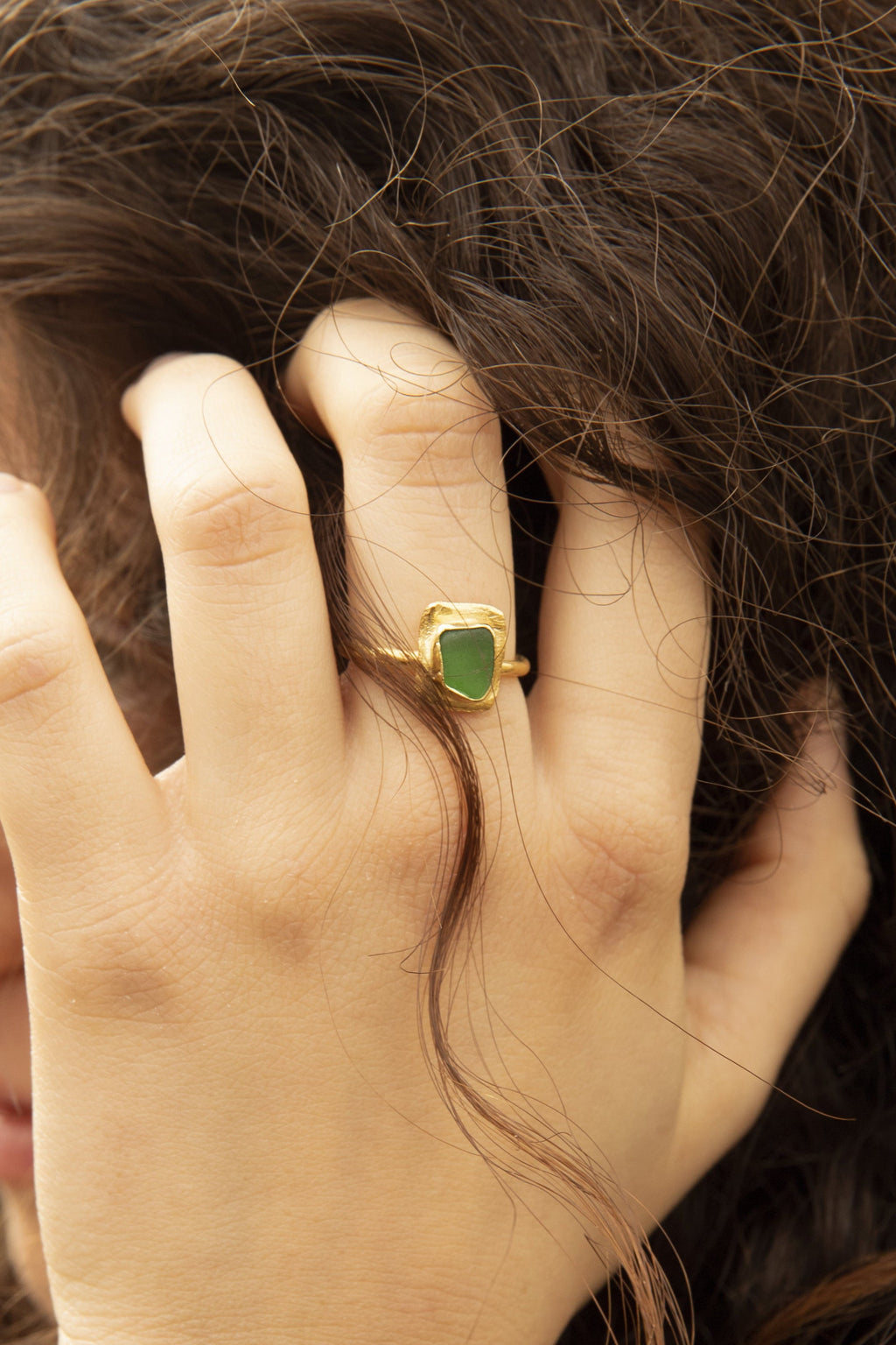 Anillo artesanal bañado en oro con cristal verde natural. Diseño escultural hecho a mano. Foto detalle modelo. 