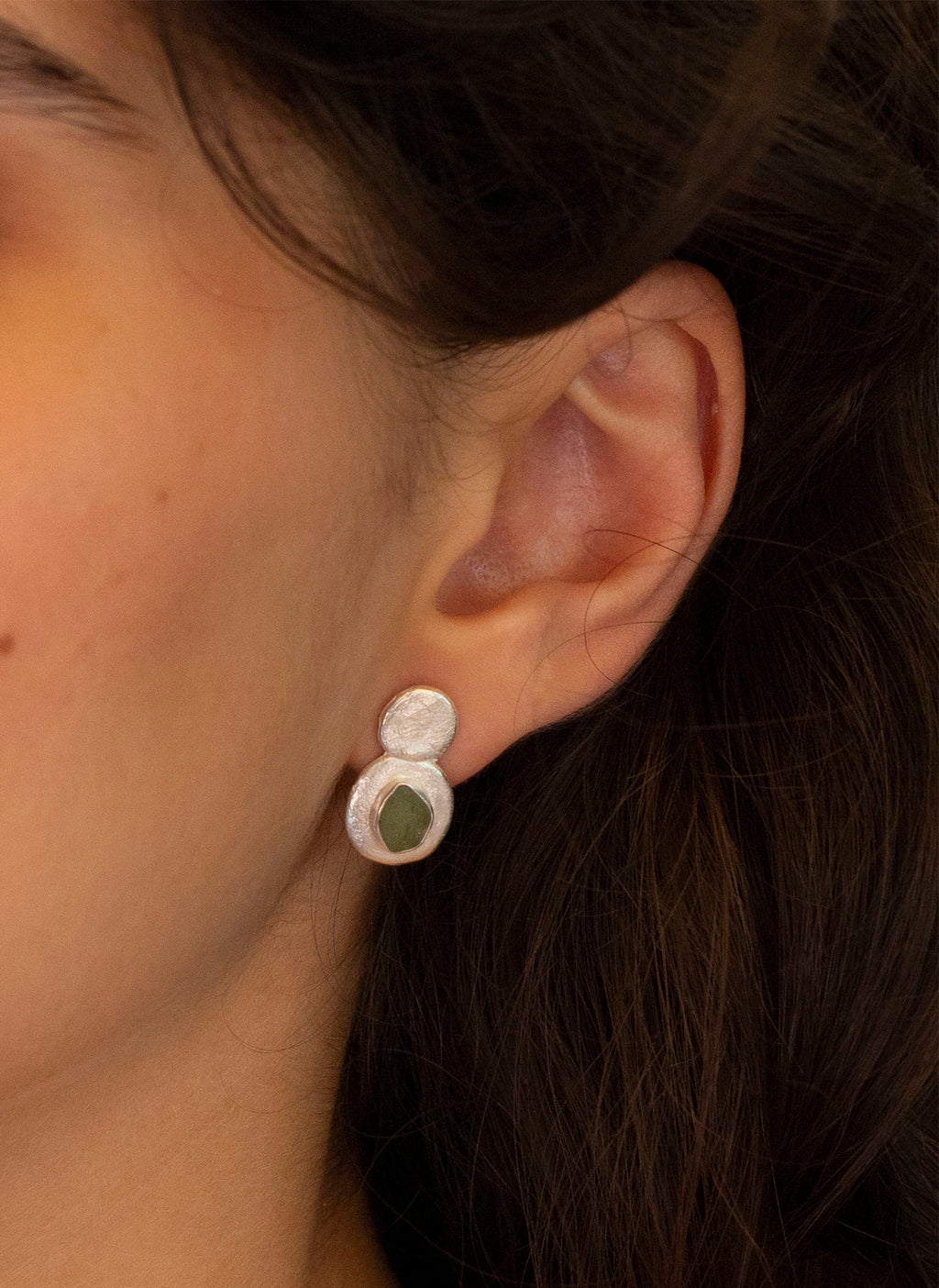 Pendientes artesanales con cristales verdes clavados y detalles en la parte superior, en plata. Foto modelo. 