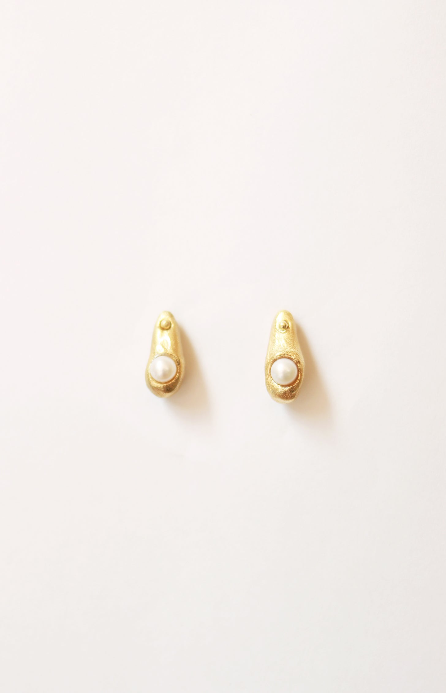 Pendientes artesanales en forma de gota con una perla cultivada incrustada, bañados en oro. Foto detalle.