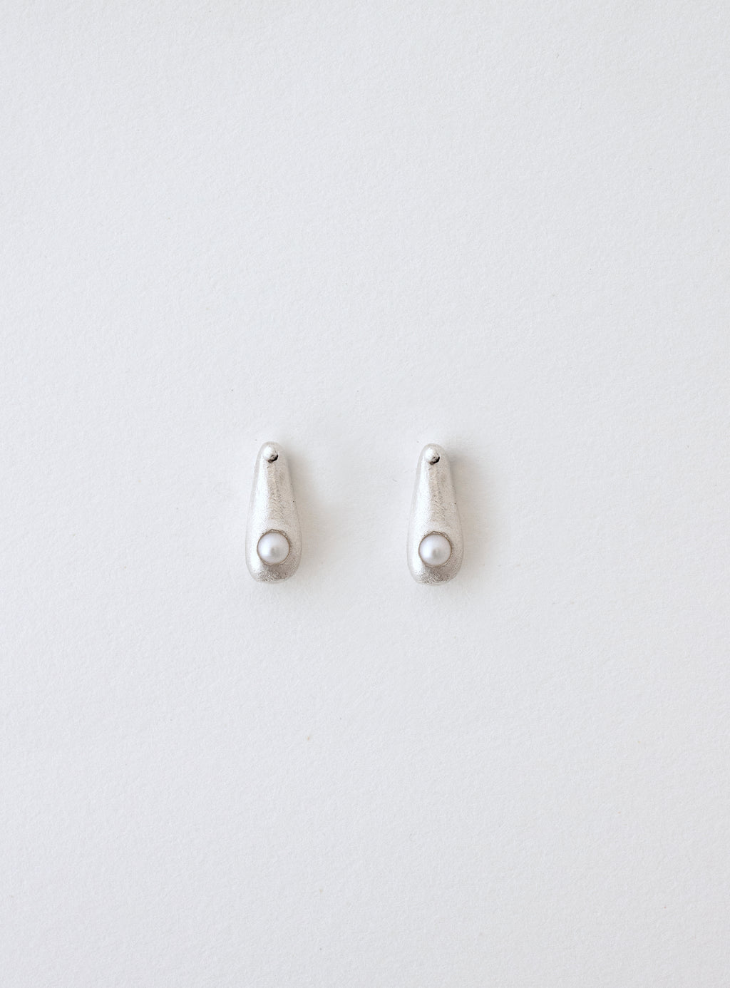 Pendientes artesanales en forma de gota con una perla cultivada incrustada, en plata. Foto detalle.