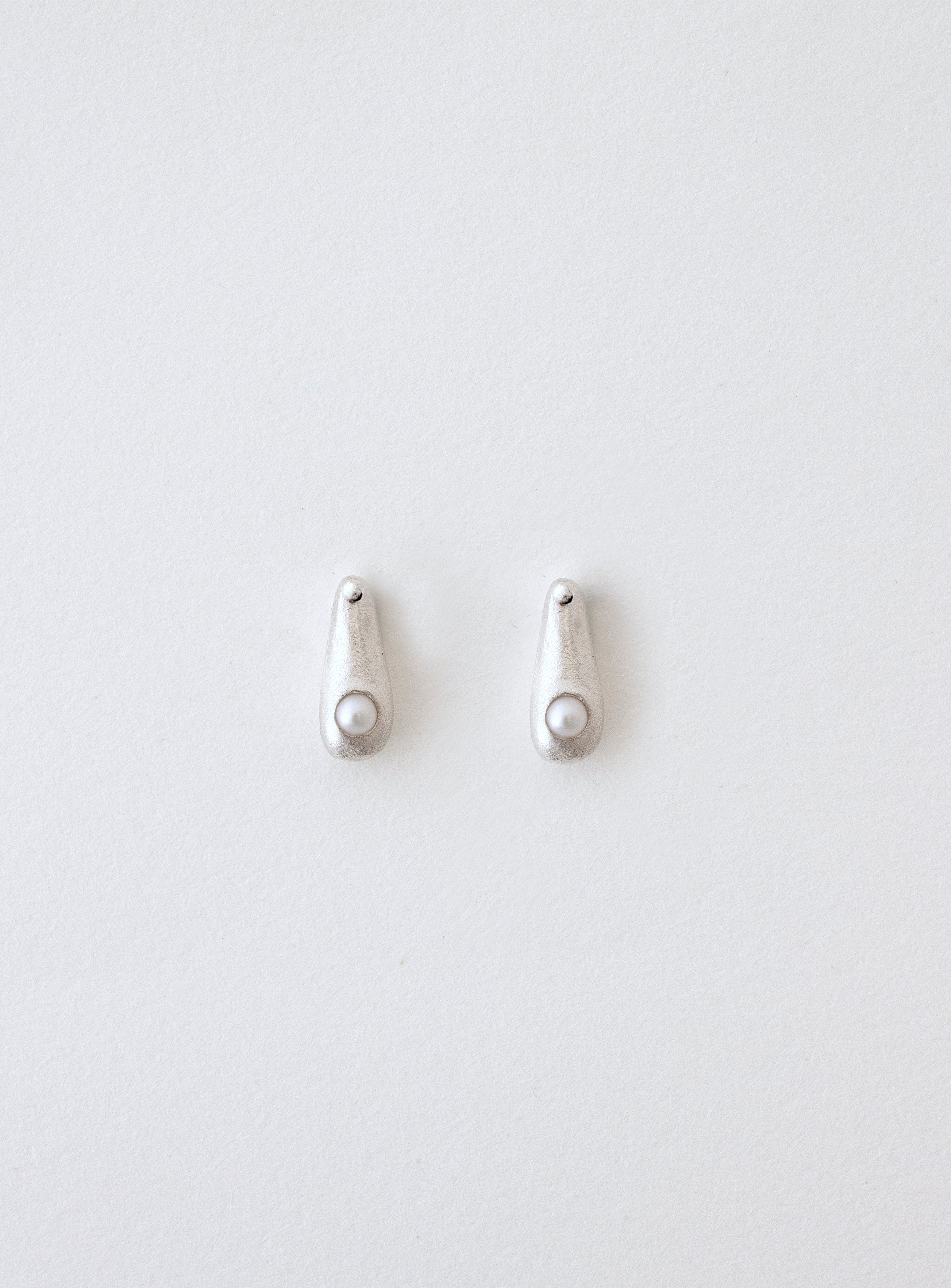 Pendientes artesanales en forma de gota con una perla cultivada incrustada, en plata. Foto detalle.