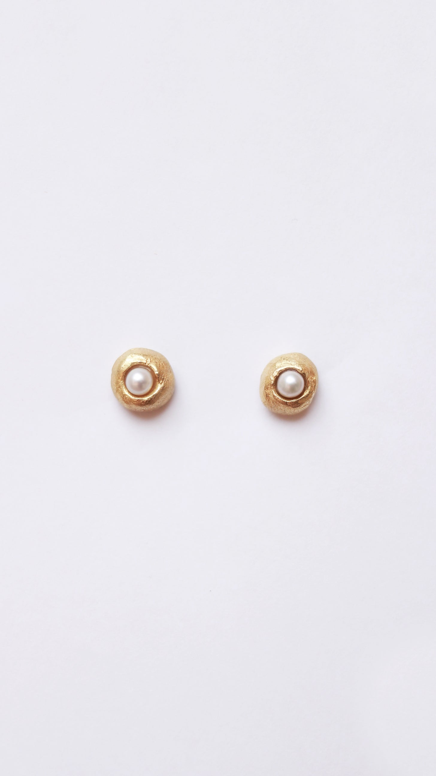 Pendientes artesanales con perla cultivada clavada en forma redonda, en oro. Foto detalle producto.